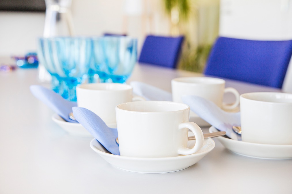 Ett mötesbord dukat med kaffekoppar och vattenglas.